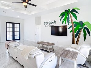 A modern living room with a sofa, a coffee table, and a TV mounted on the wall. - Boca Grande Retreat Sleeps 10 (Port Charlotte)