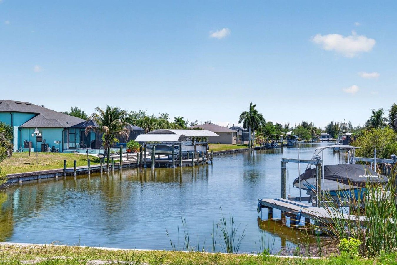 A waterfront property with a dock, a covered area, and a house with a blue exterior.