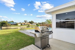An outdoor grill area with a pool in the background. - Punta Gorda Waterfront Retreat Pool Sleep 10 (Port Charlotte)