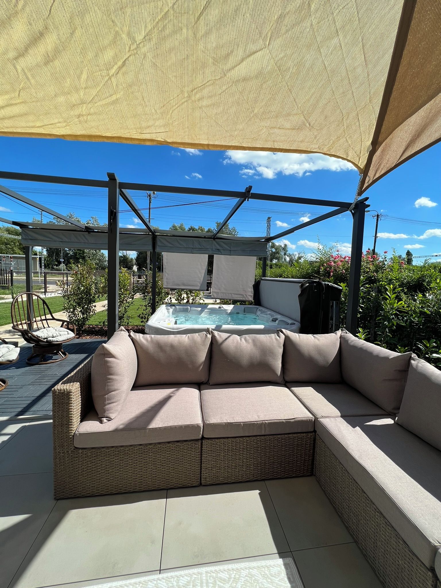 A covered outdoor seating area with a hot tub and a view of the surrounding landscape.