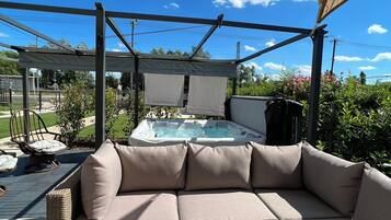 A covered outdoor seating area with a hot tub and a view of the surrounding landscape.