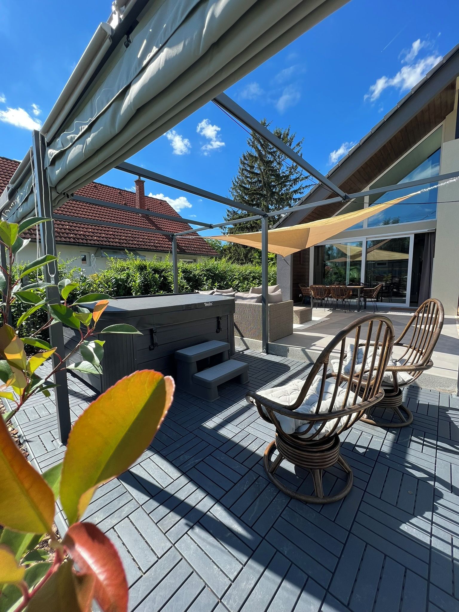 Una terrazza esterna con un barbecue, un'area salotto e vista su una casa.