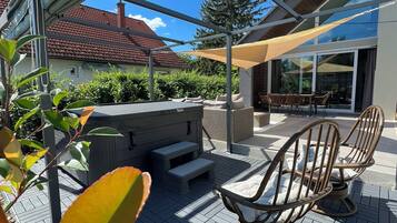 Una terrazza esterna con un barbecue, un'area salotto e vista su una casa.