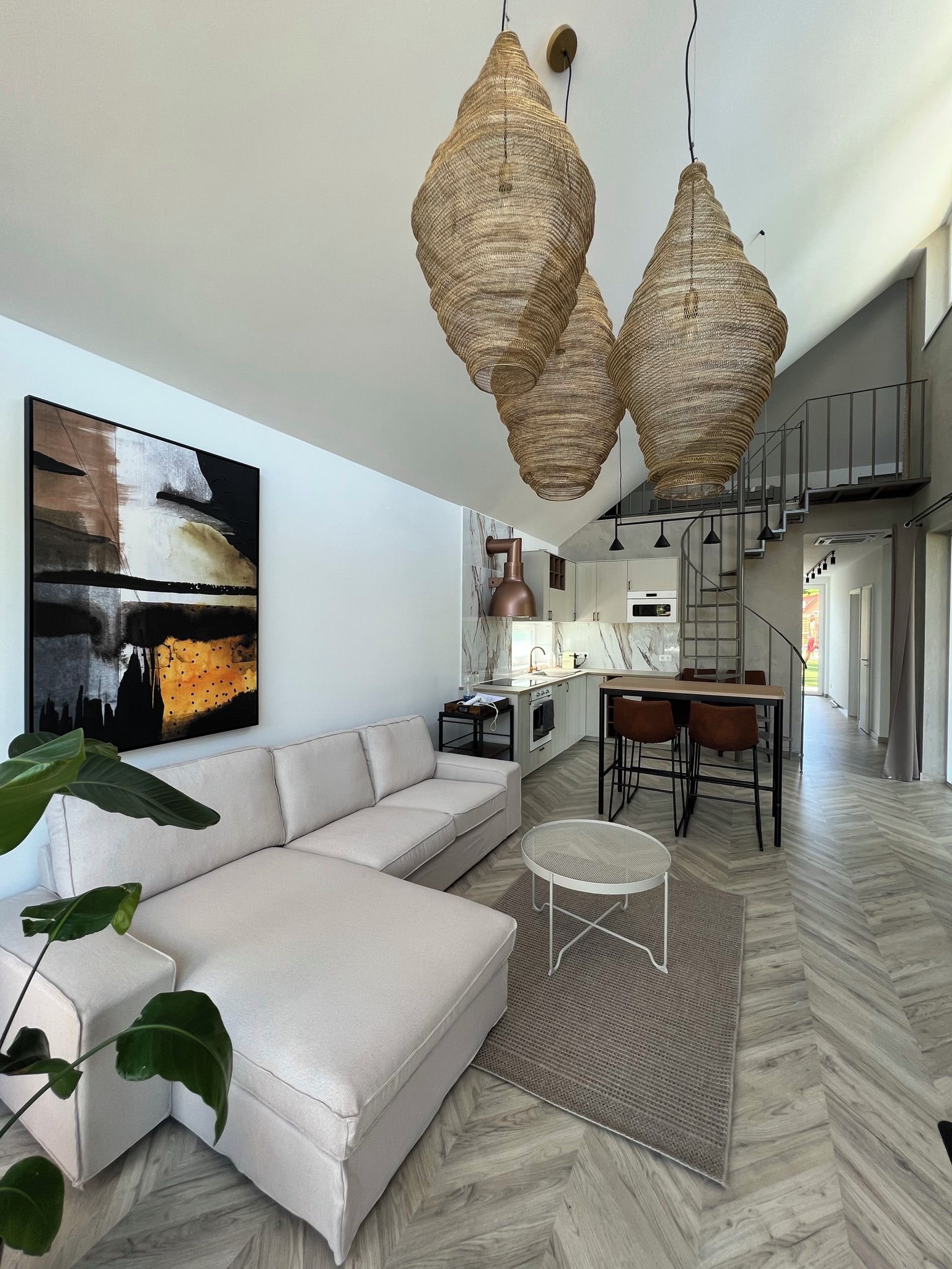 Ein modernes Wohnzimmer mit einem weißen Sofa, einem Essbereich mit Tisch und Stühlen sowie einer Küche mit weißen Schränken.