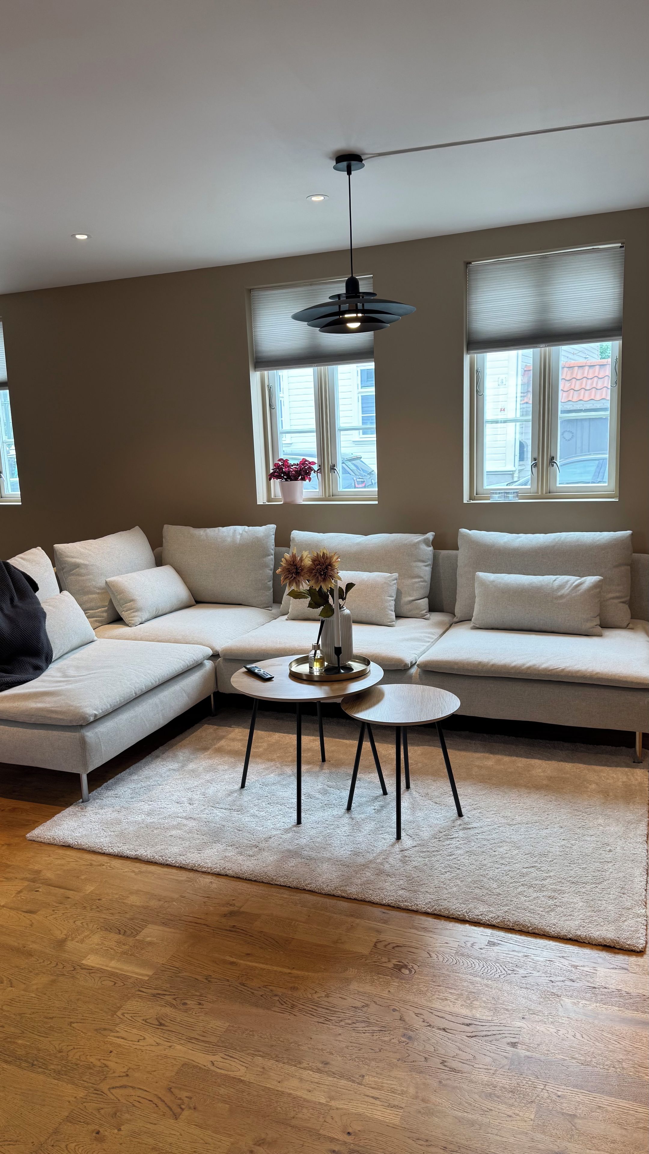 A modern living room with a sectional sofa, a coffee table, and a hanging light fixture.