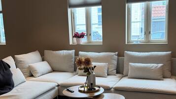 A modern living room with a sectional sofa, a coffee table, and a hanging light fixture.