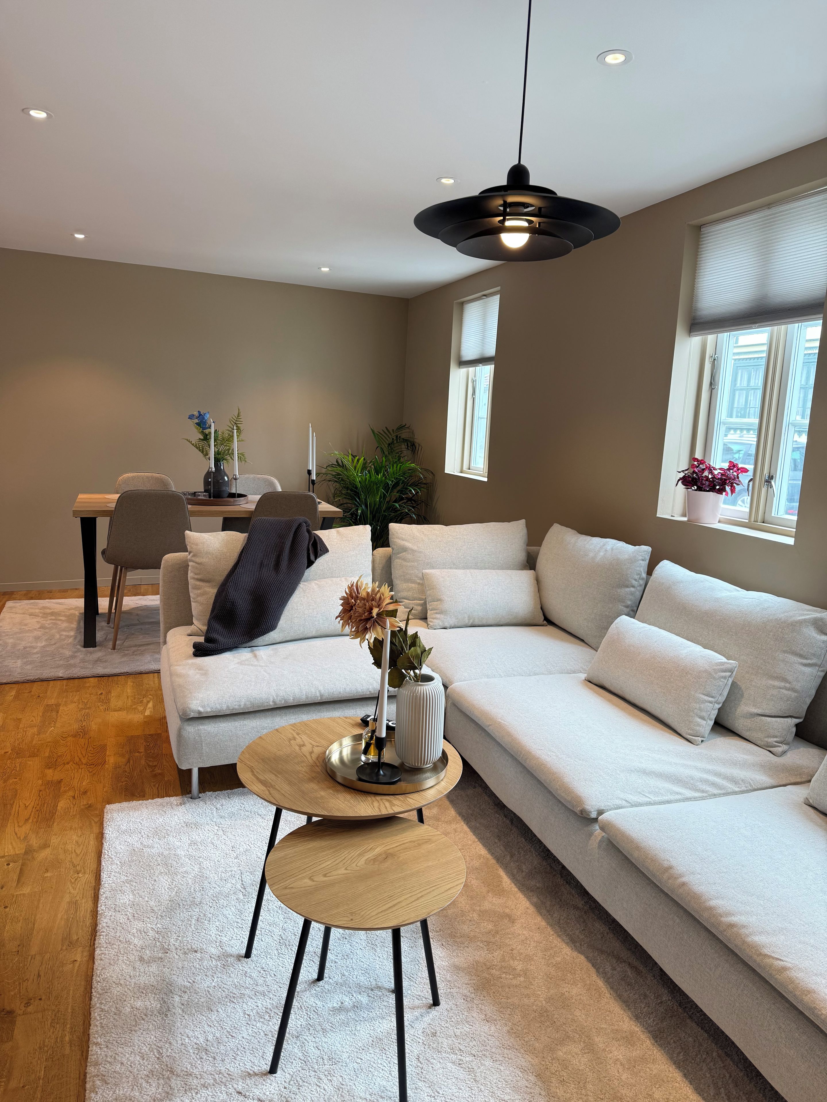 A modern living room with a sectional sofa, a round coffee table, and a dining area with a chair and table.