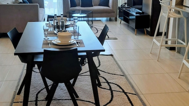 Uma sala de estar moderna com área de jantar, janelas amplas e televisão de tela plana.