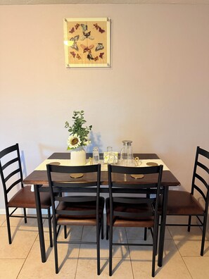 A dining table with chairs, a vase with flowers, and a framed butterfly artwork on the wall. - Gorgeous 3-bedroom house with AC in charming Eugene (Eugene)