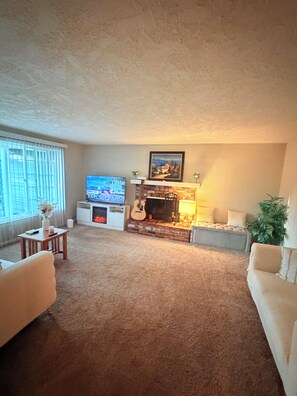 A living room with a fireplace, a television, and a sofa. - Gorgeous 3-bedroom house with AC in charming Eugene (Eugene)