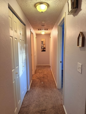 A hallway with carpeted floors, white walls, and a ceiling light fixture. - Gorgeous 3-bedroom house with AC in charming Eugene (Eugene)