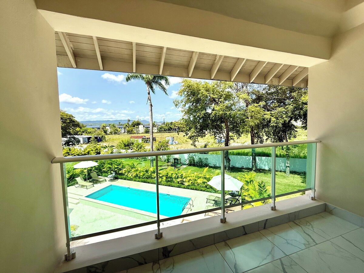 Un balcón con vista a una piscina y follaje.
