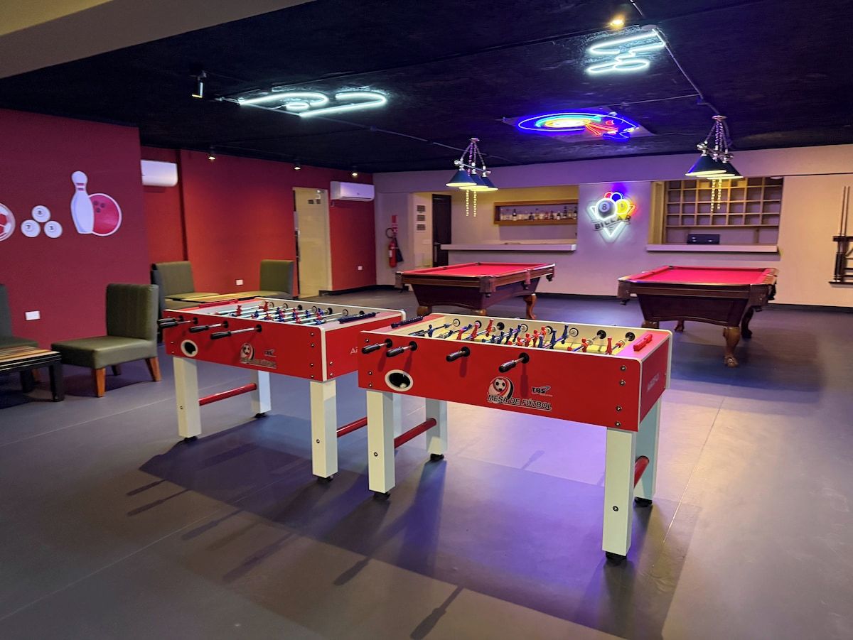 A room with two foosball tables, a pool table, and a billiards table.