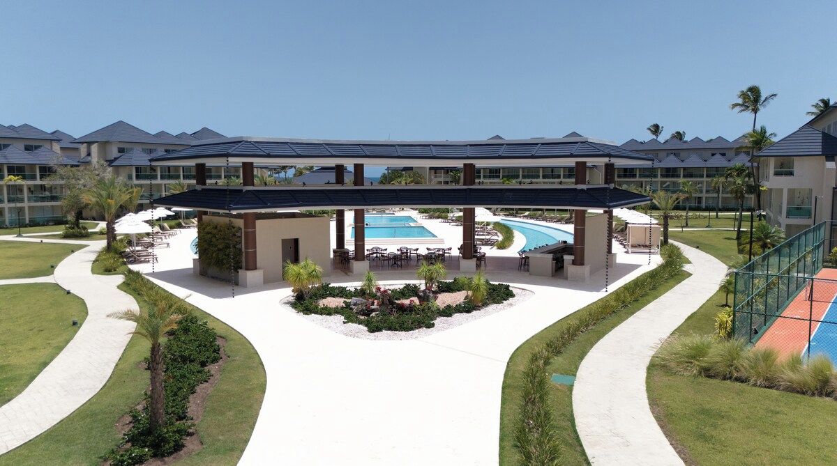 Un resort con piscina, zonas de estar cubiertas y un jardín ajardinado.