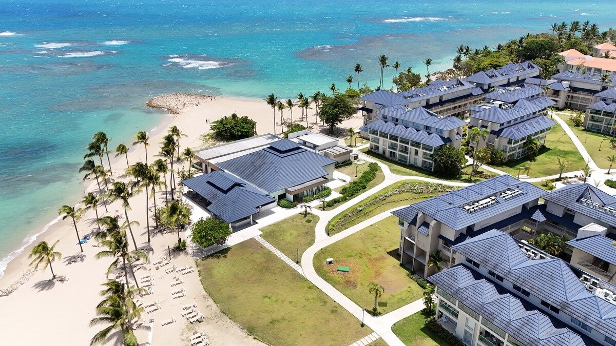 Un complexe hôtelier comprenant plusieurs bâtiments, une plage et des palmiers.