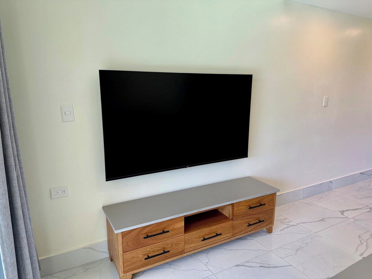 Un televisor de pantalla plana montado en una pared sobre un mueble de televisión de madera con cajones.