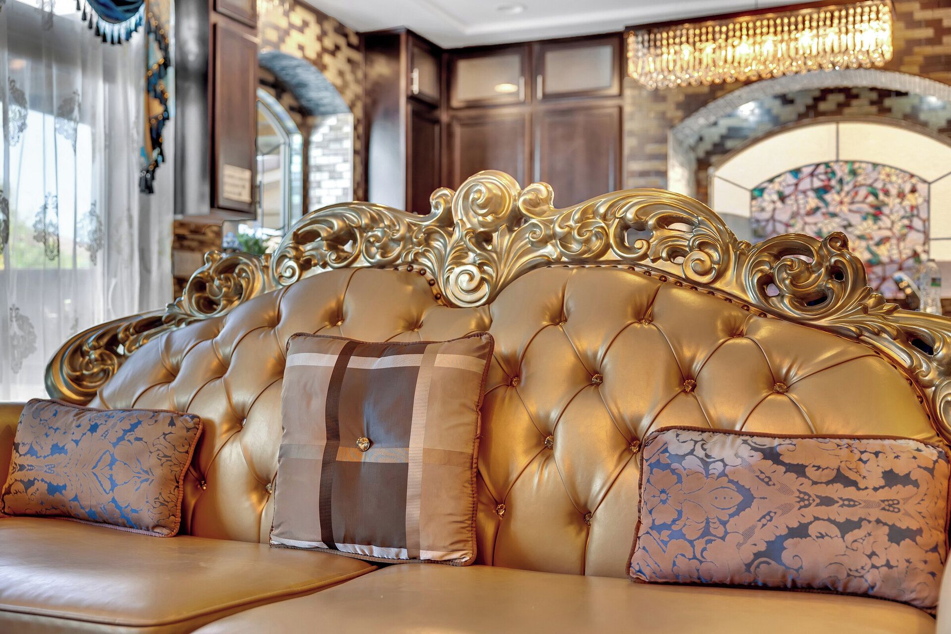 A luxurious sofa with ornate gold detailing and tufted upholstery.