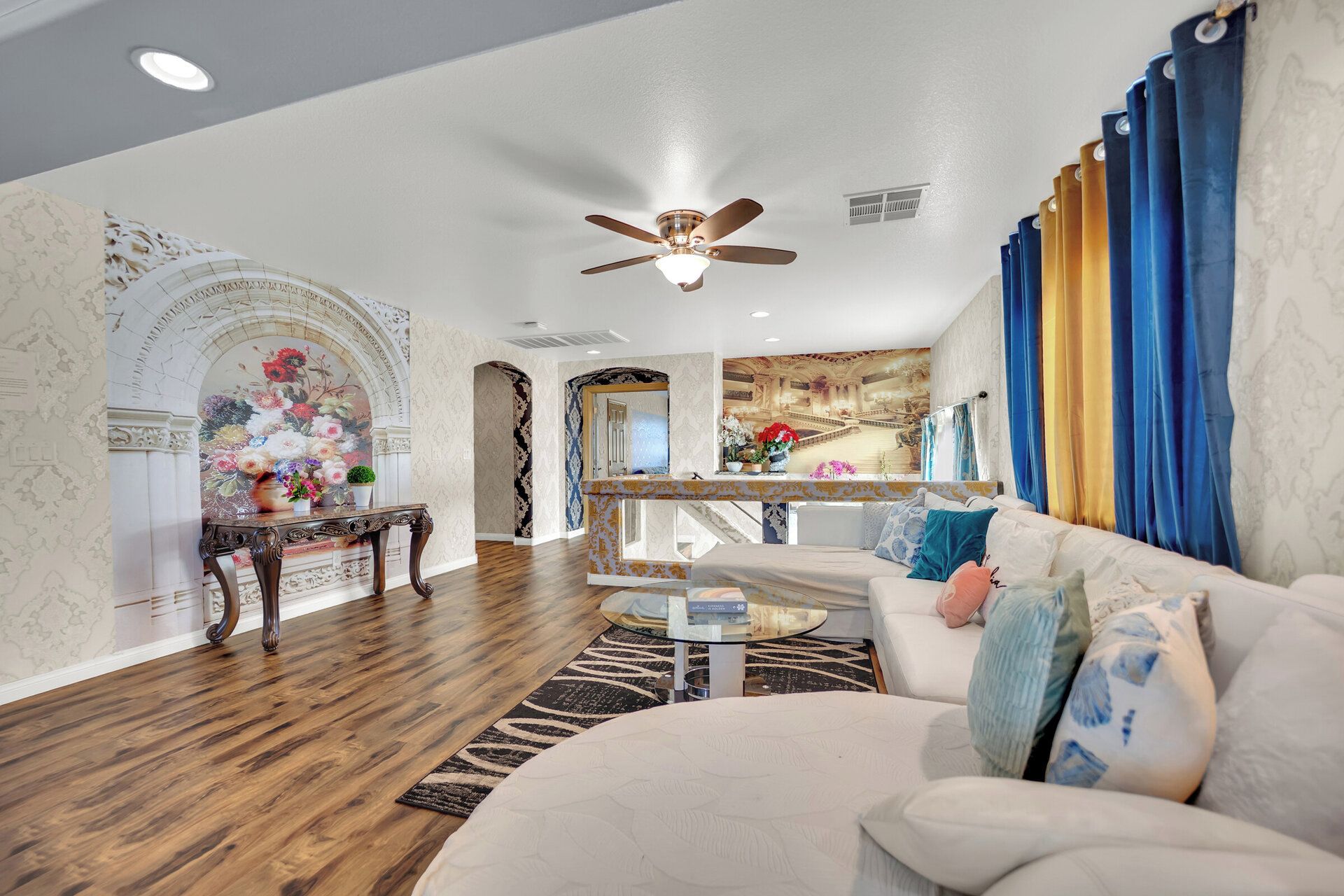 A spacious living room with a white sofa, a coffee table, and a decorative mirror.