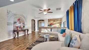 A spacious living room with a white sofa, a coffee table, and a decorative mirror.