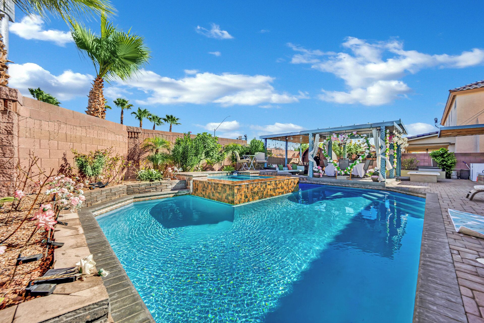 A swimming pool with a wooden deck and a covered seating area.