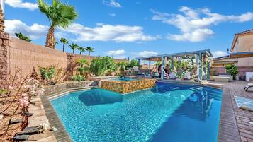 A swimming pool with a wooden deck and a covered seating area.