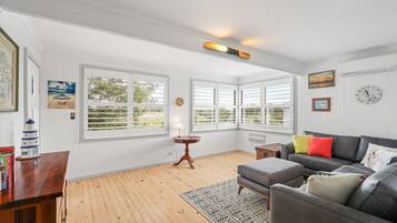 A living room with a grey sofa, a patterned rug, and a wooden floor.