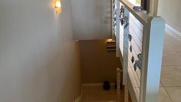 Un escalier avec une rampe, un luminaire fixé au mur et un panneau avec du texte.