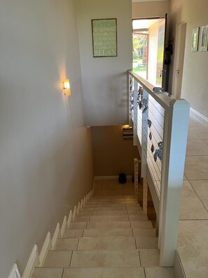 A staircase with a handrail, a wall-mounted light, and a sign with text.