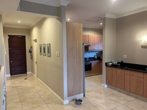 A modern kitchen with wooden cabinets, a black countertop, and a tiled floor.