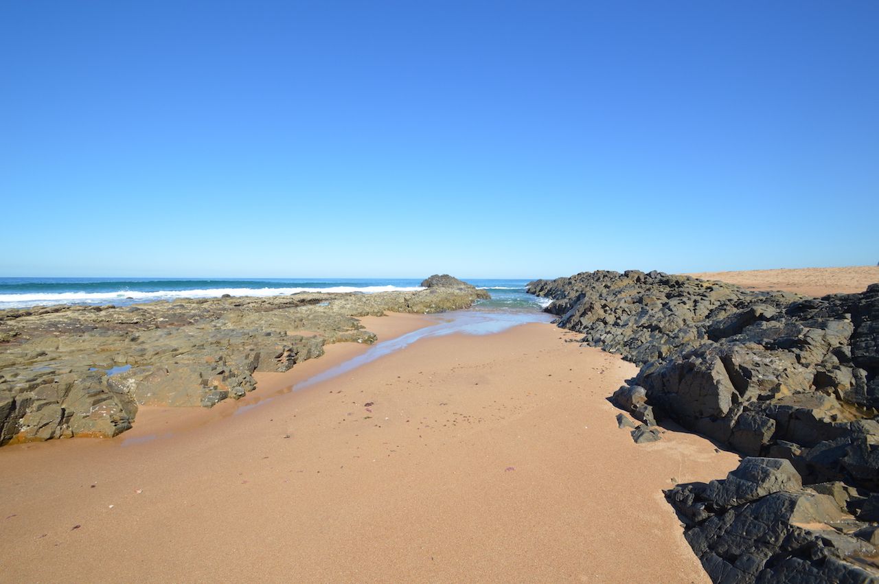 Una spiaggia con terreno roccioso e cielo sereno.