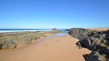 Une plage au paysage rocheux, sous un ciel dégagé.
