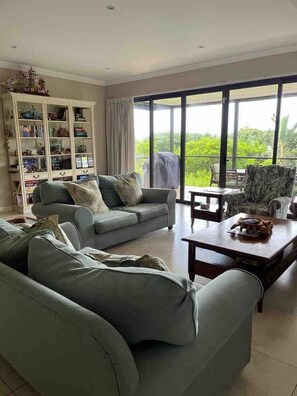A living room with a grey sofa set, a coffee table, and a bookshelf.
