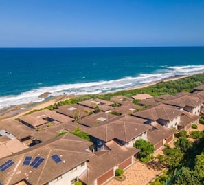 A coastal residential area with houses featuring sloped roofs and solar panels.