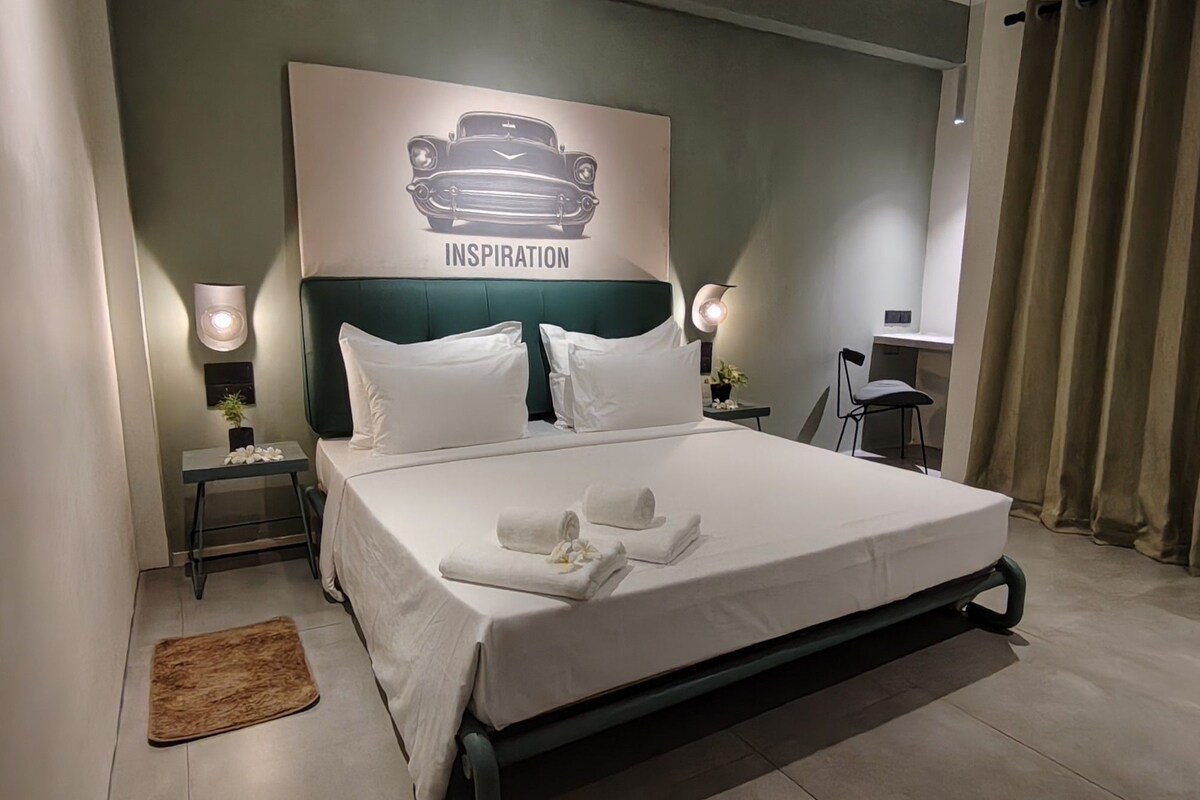 A neatly made bed with white linens, a headboard with a car illustration, and two bedside lamps.