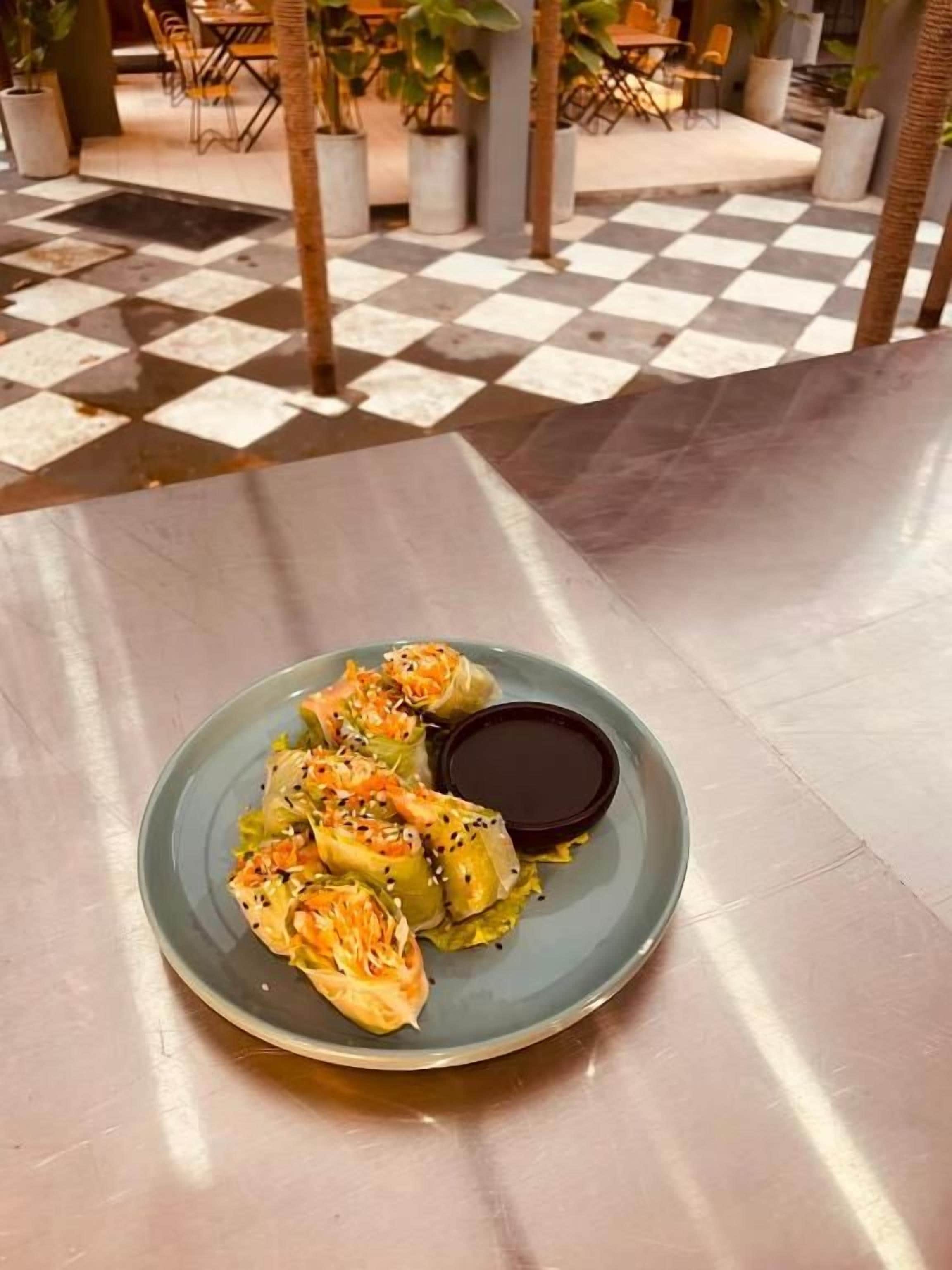 Un plato de comida con piso a cuadros y plantas en macetas al fondo.