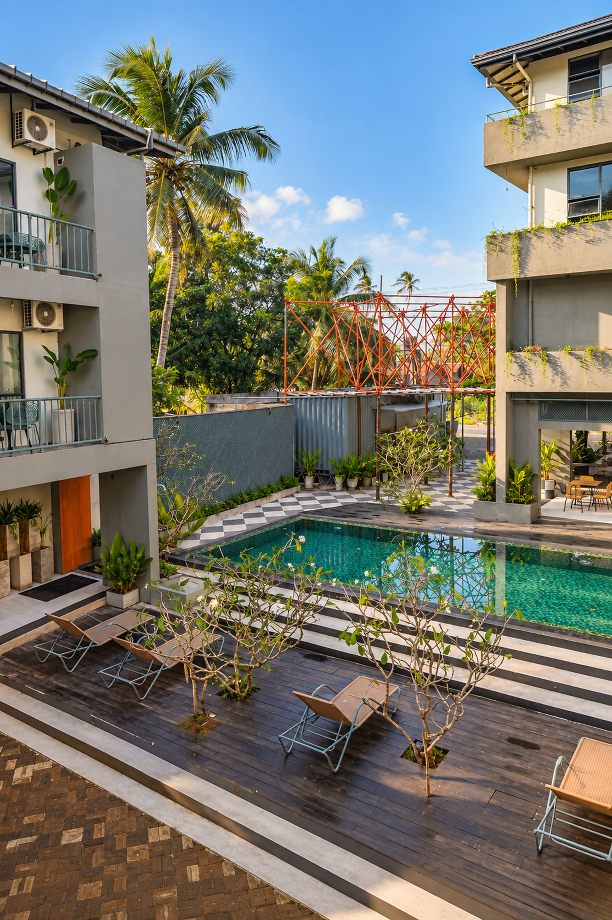 Área de piscina com espreguiçadeiras, uma piscina pequena e vegetação ao redor.