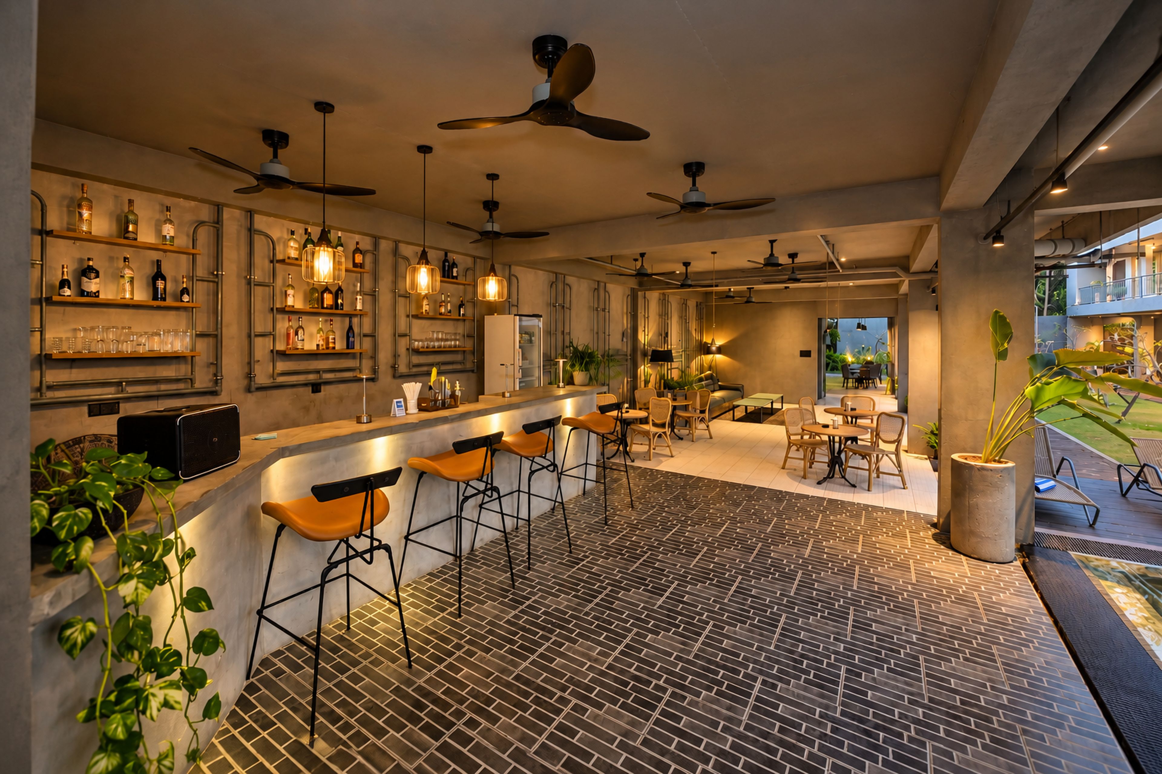 A modern bar area with high stools, ceiling fans, and a brick-patterned floor.