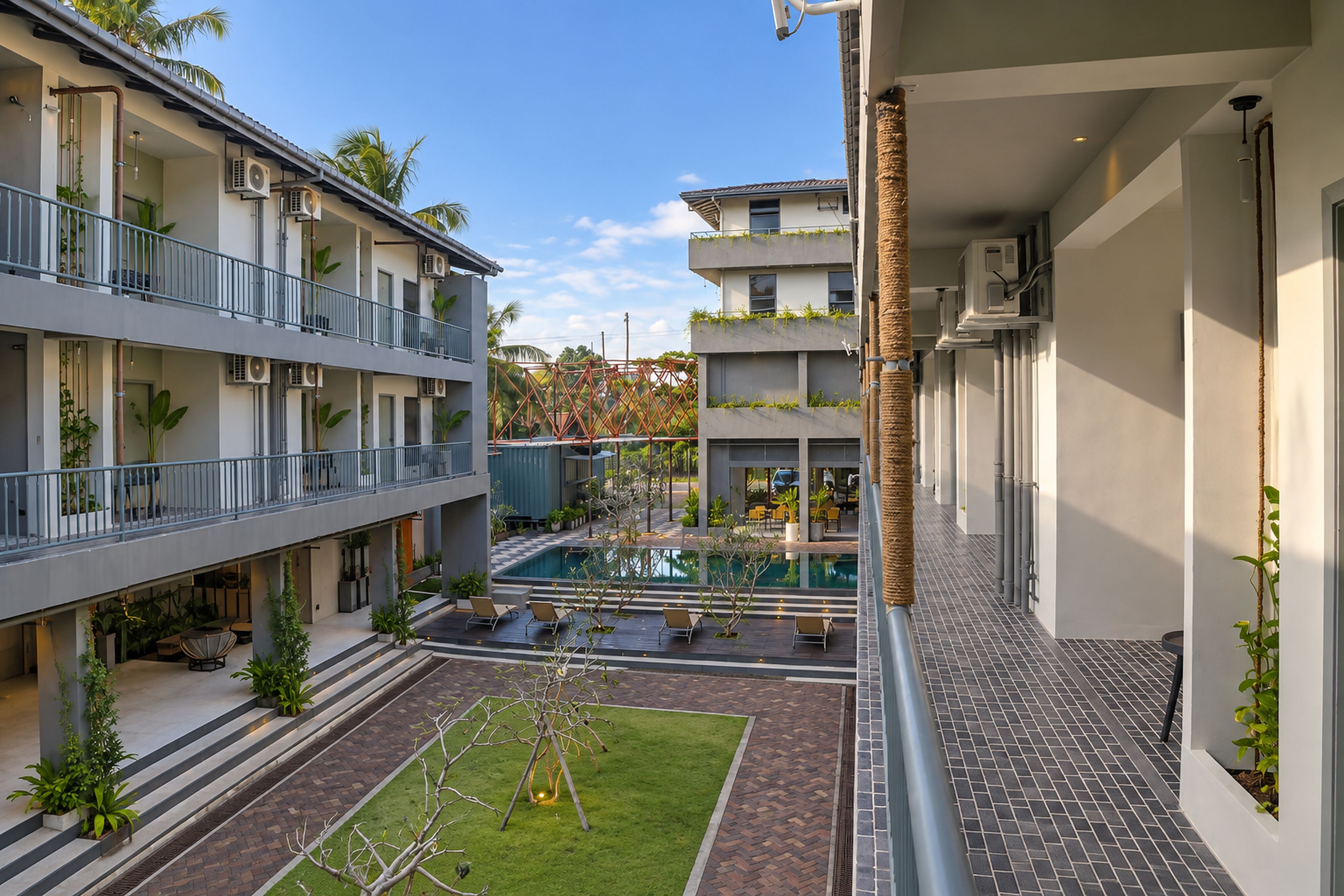 Un hotel moderno con piscina, mobiliario exterior y varios balcones.