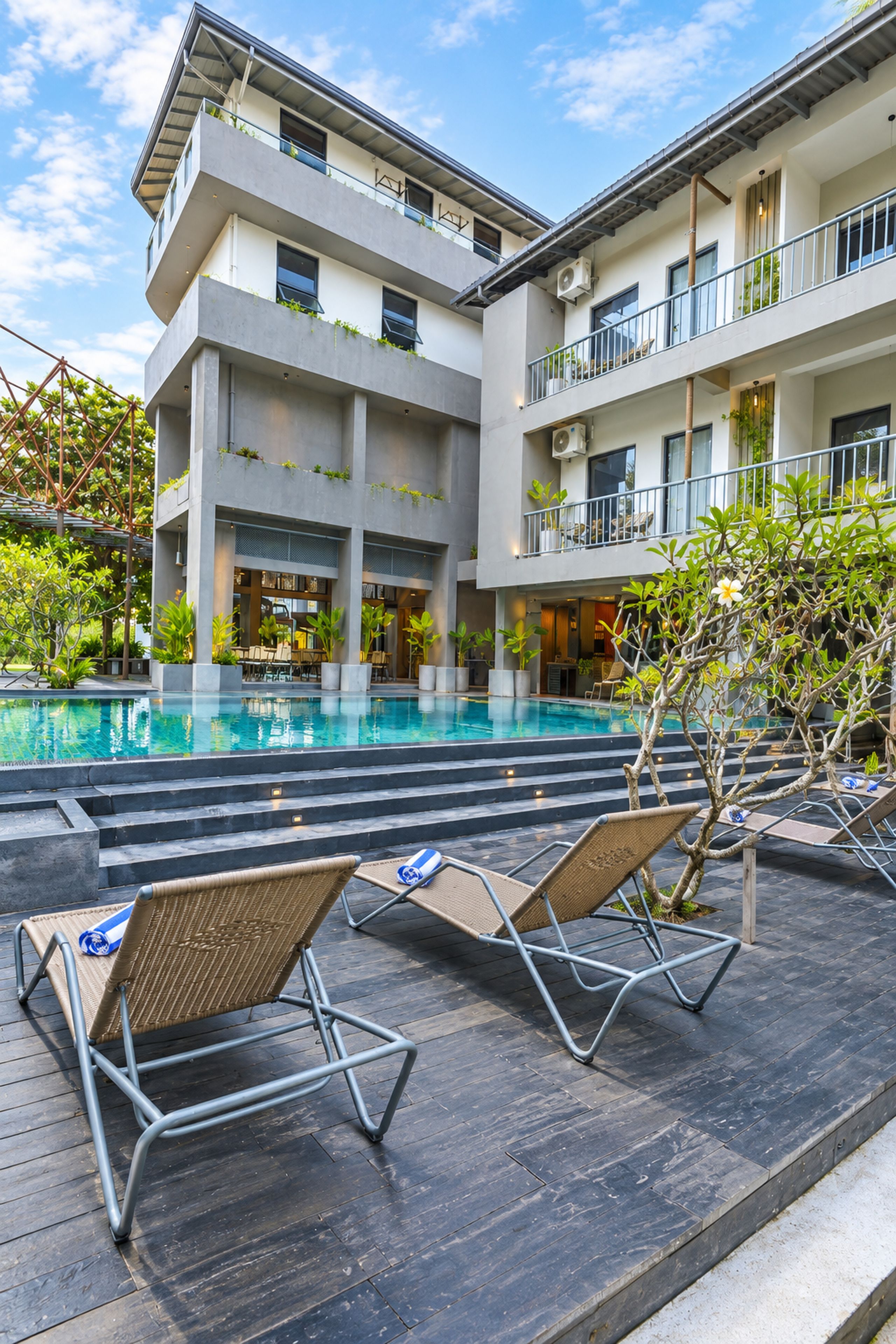 Un edificio moderno con piscina, zona de estar exterior y vegetación.