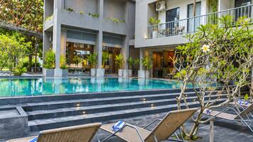 Un edificio moderno con piscina, zona de estar exterior y vegetación.