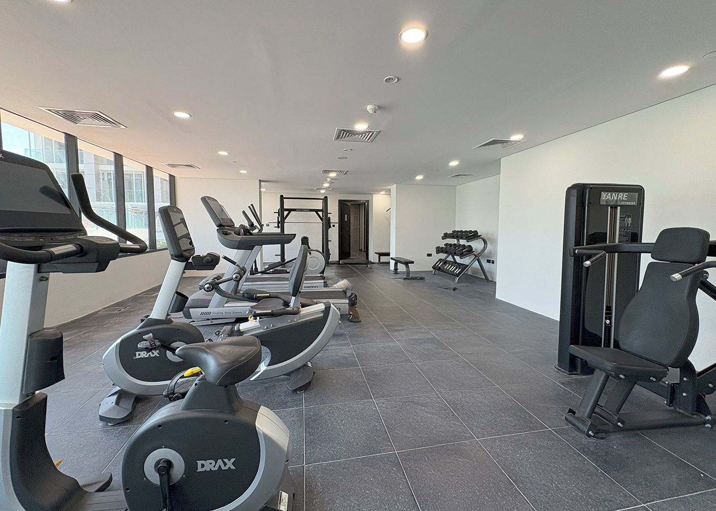Une salle de sport équipée de tapis de course, d’appareils de musculation et d’un banc.