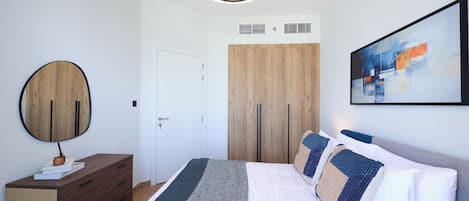 Un dormitorio moderno con cama, cómoda, espejo, un cuadro y una lámpara en el techo.