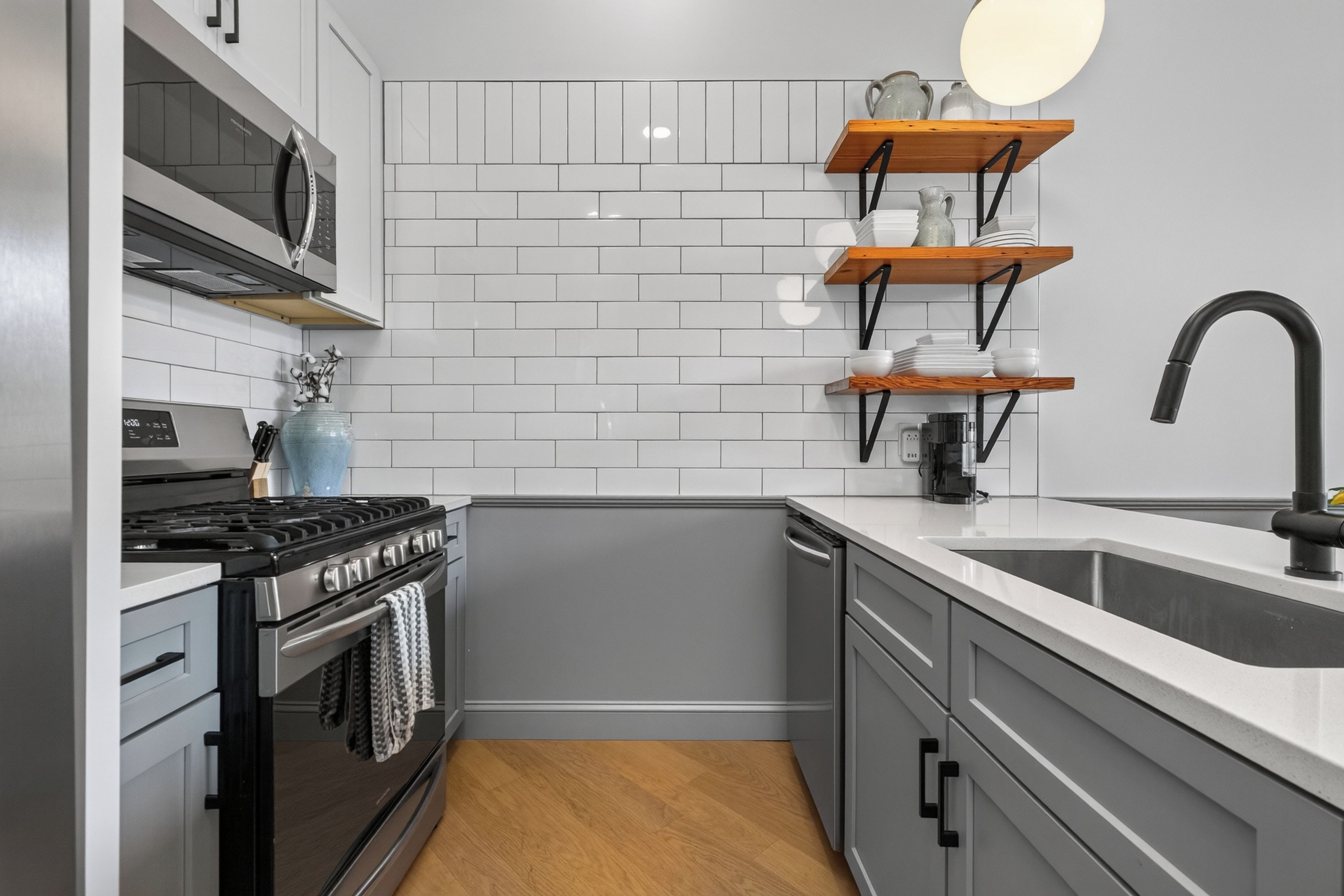 A compact kitchen with white subway tiles, a gas stove, a dishwasher, and a black faucet.