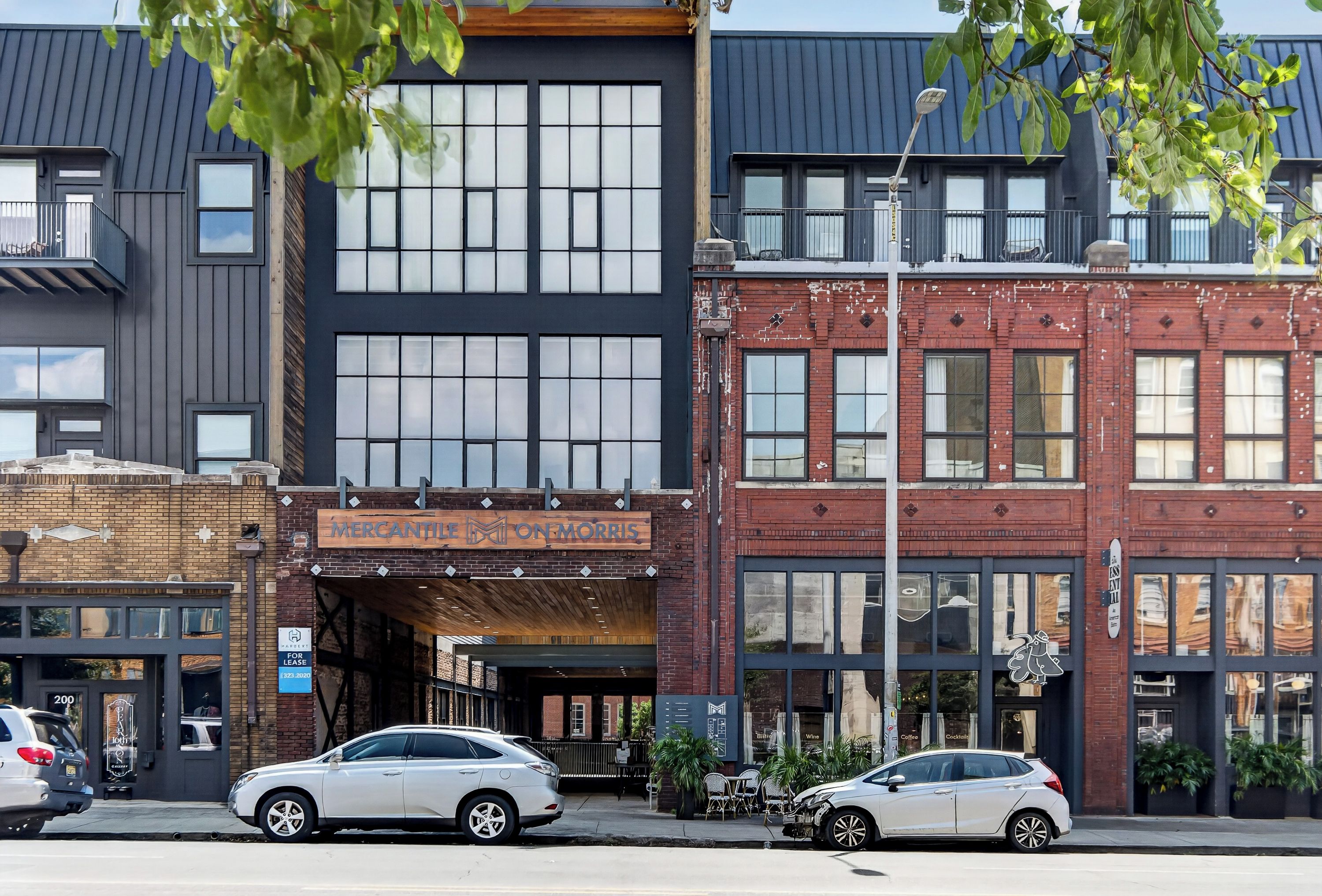 A street view with buildings, including a Mercantile on Morris with a wooden sign, and parked cars.