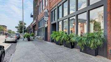 Une vue de rue avec un bâtiment doté de grandes fenêtres et d’une enseigne indiquant « The ESSENTIAL American Bistro ».