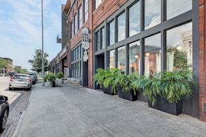 A street view with a building featuring large windows and a sign for 'The ESSENTIAL American Bistro.'