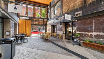 An outdoor café area with brick walls, wooden ceiling, and seating arrangements.