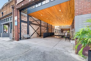 A building with a brick facade, large windows, and a covered outdoor area with a wooden ceiling.