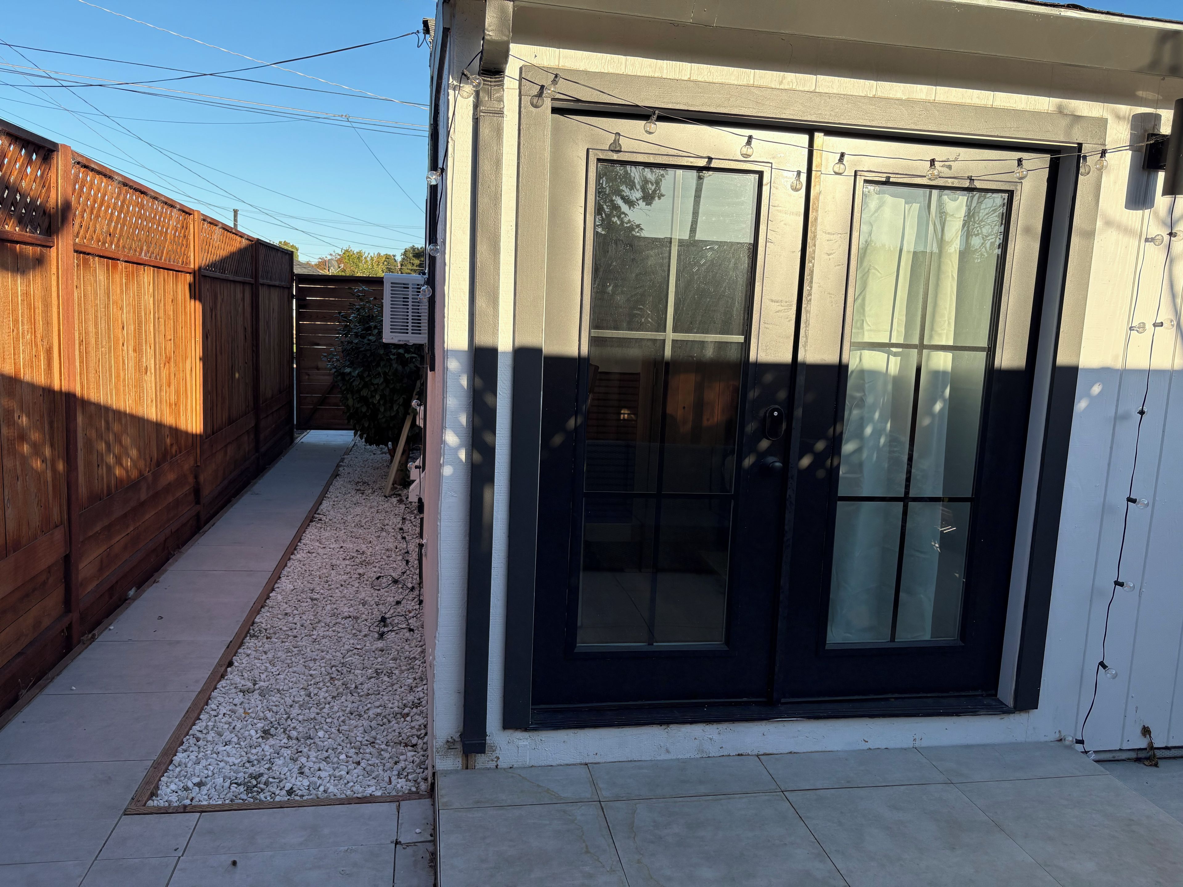 A residential property with a wooden fence, a gravel pathway, and a black sliding door.
