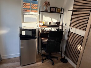 Une petite cuisine équipée comprenant un réfrigérateur, un four à micro-ondes et une petite table à manger avec une chaise.